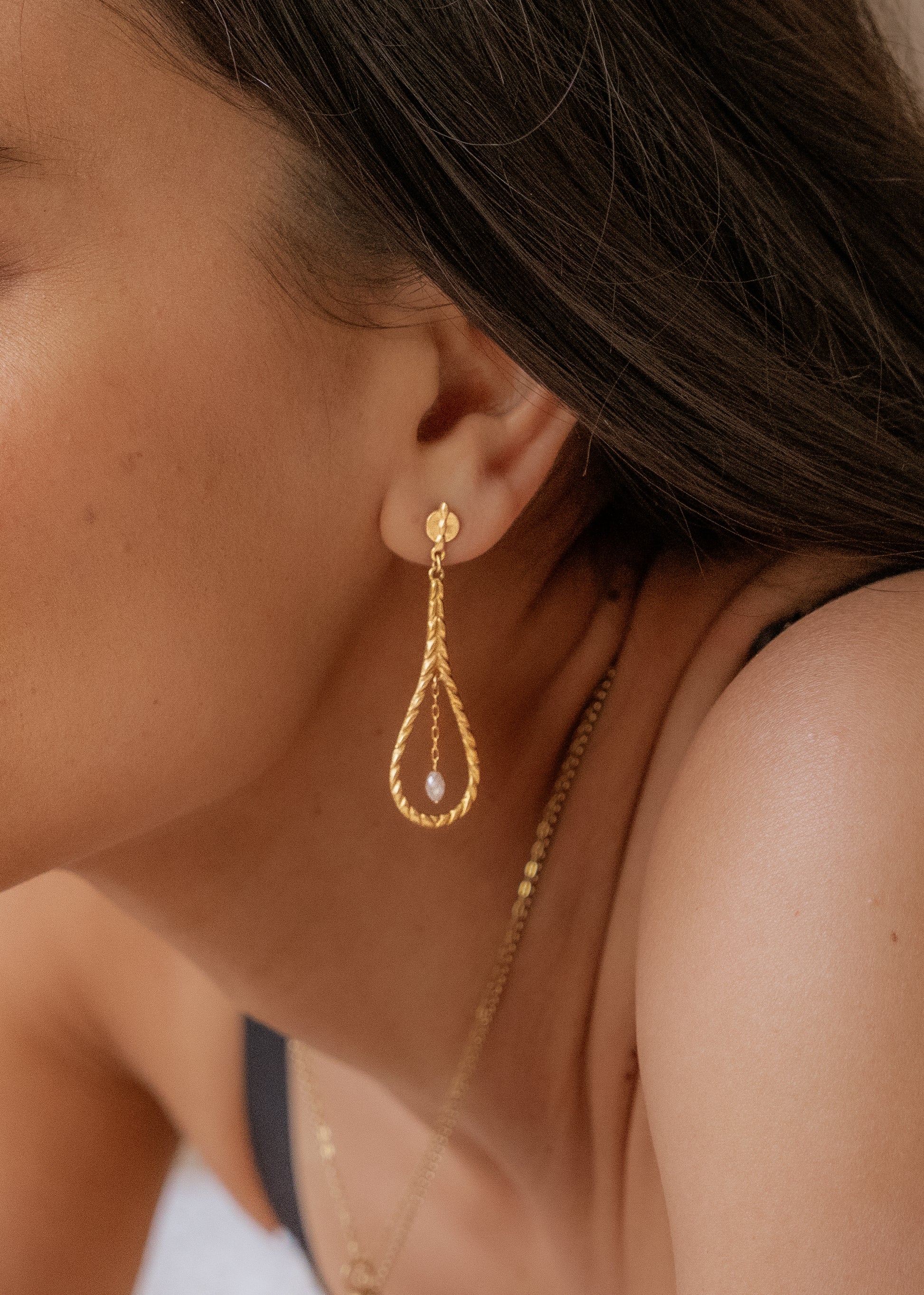 Like a song of the Siren, the Anchor earring seduces its wearer with exquisite craftsmanship and use of negative space. The hand-carved, rope-like detail highlights the elongated shape, lending an elegant nautical touch. Inside, diamond beads dangle from a delicate chain, a glint of sunlight on water that draws the eye in and captivates.