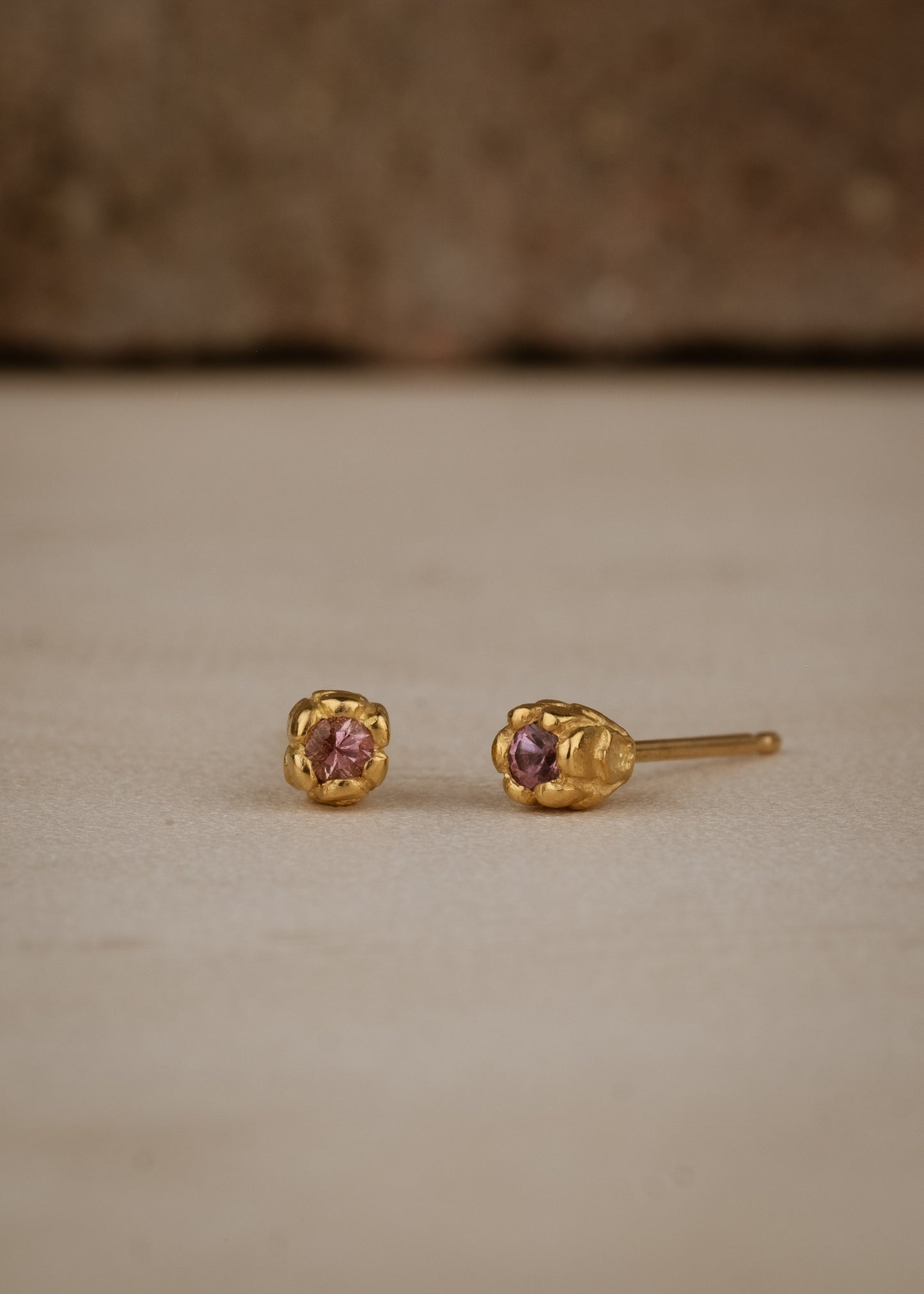 Inspired by a set of rings purchased for a childhood crush, the Bey earrings merge the simplicity of days past with a refined sophistication. Hand-crafted gold petals form a cocoon around a stunning pink sapphire, creating delicate earrings perfect for celebrating the everyday.