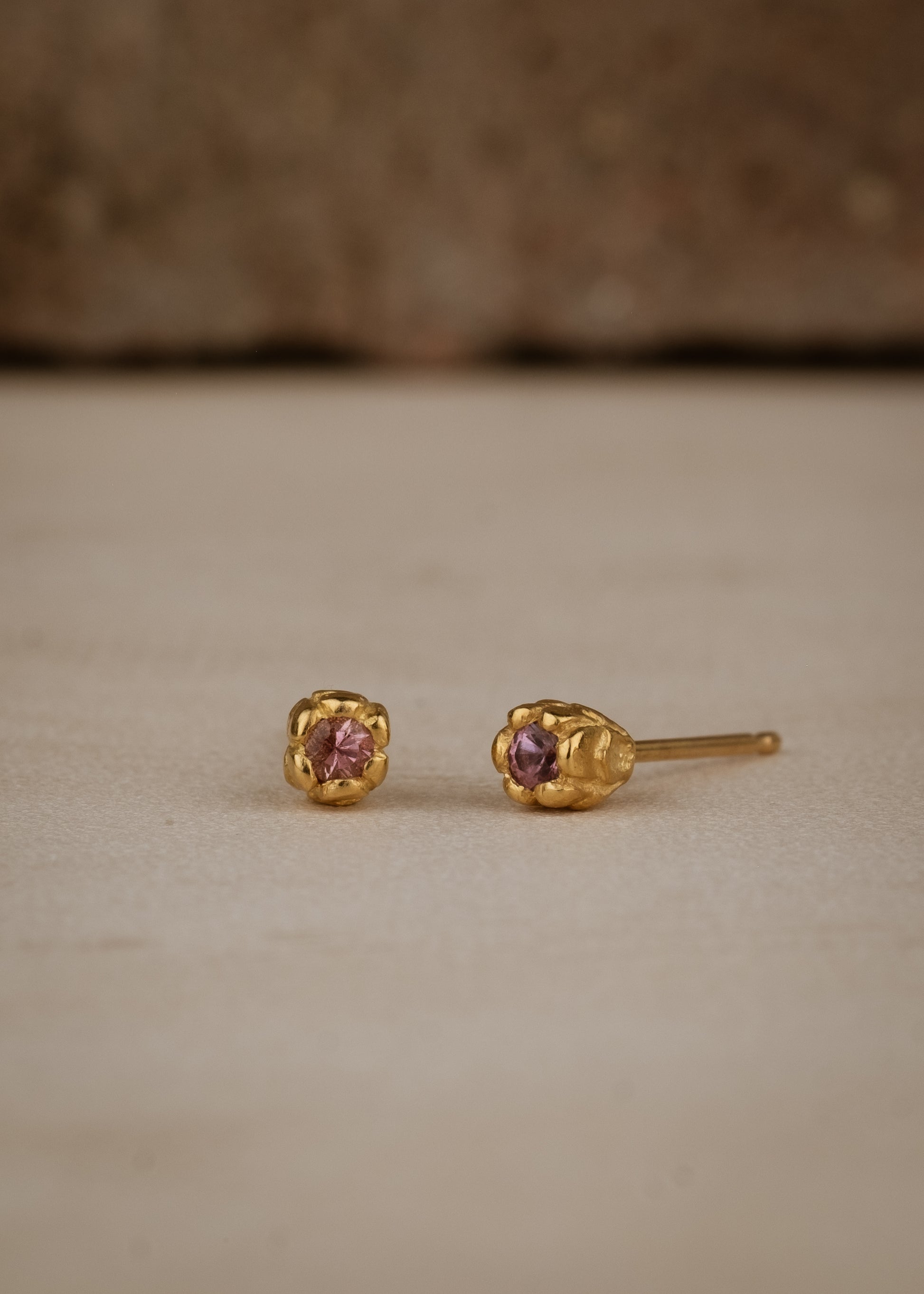 Inspired by a set of rings purchased for a childhood crush, the Bey earrings merge the simplicity of days past with a refined sophistication. Hand-crafted gold petals form a cocoon around a stunning pink sapphire, creating delicate earrings perfect for celebrating the everyday.
