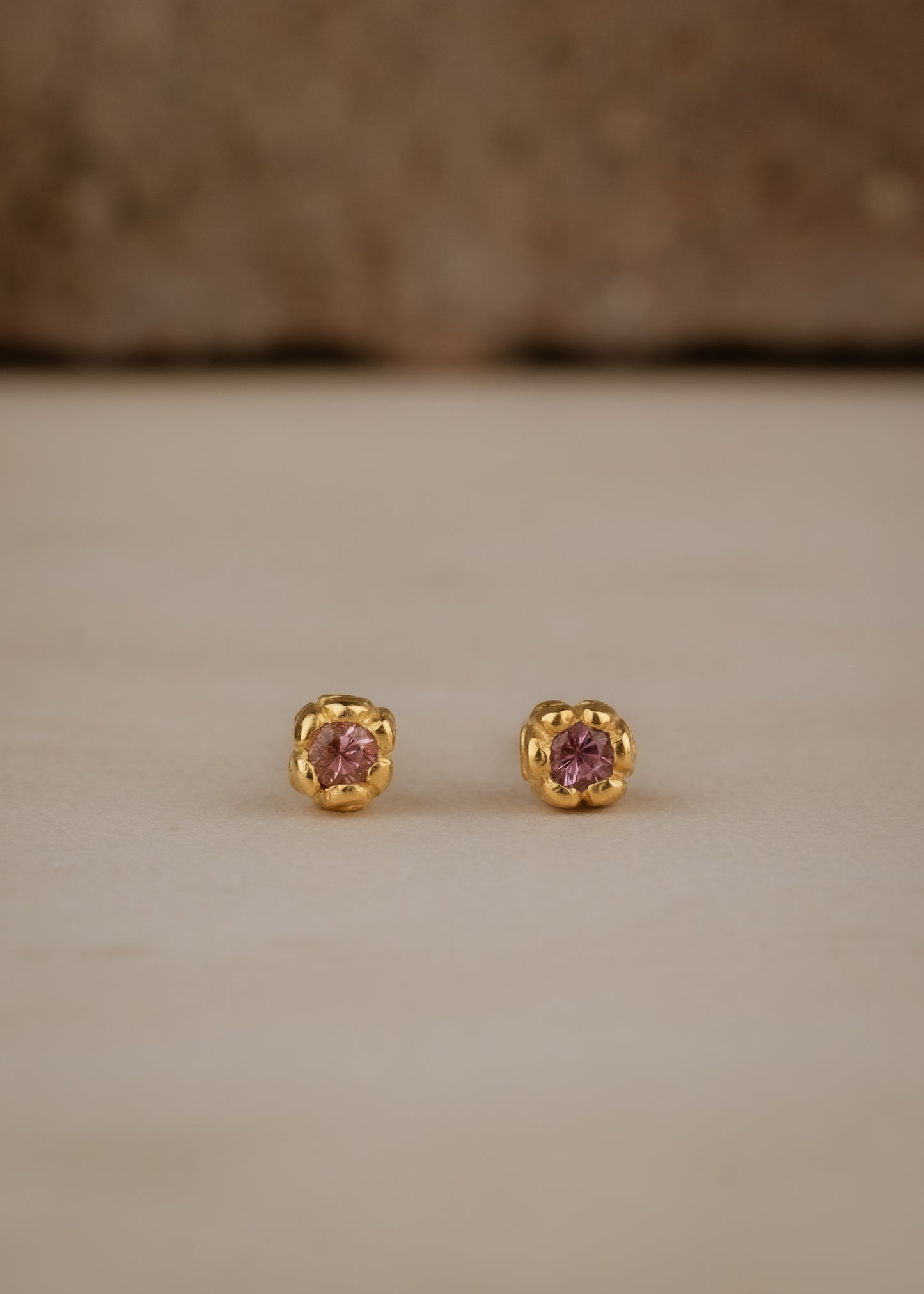 Inspired by a set of rings purchased for a childhood crush, the Bey earrings merge the simplicity of days past with a refined sophistication. Hand-crafted gold petals form a cocoon around a stunning pink sapphire, creating delicate earrings perfect for celebrating the everyday.