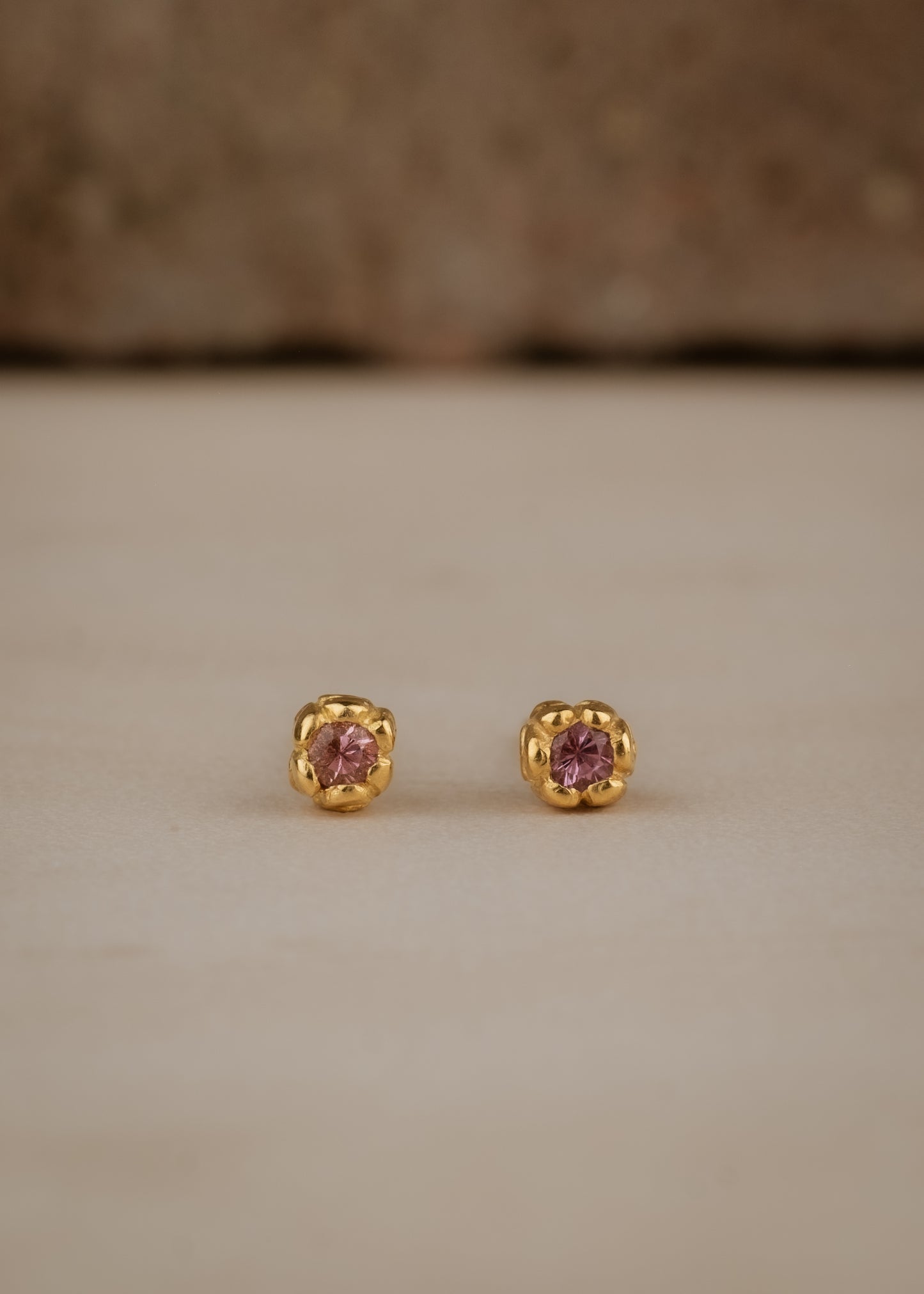 Inspired by a set of rings purchased for a childhood crush, the Bey earrings merge the simplicity of days past with a refined sophistication. Hand-crafted gold petals form a cocoon around a stunning pink sapphire, creating delicate earrings perfect for celebrating the everyday. 