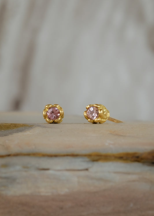 Inspired by a set of rings purchased for a childhood crush, the Bey earrings merge the simplicity of days past with a refined sophistication. Hand-crafted gold petals form a cocoon around a stunning pink sapphire, creating delicate earrings perfect for celebrating the everyday.
