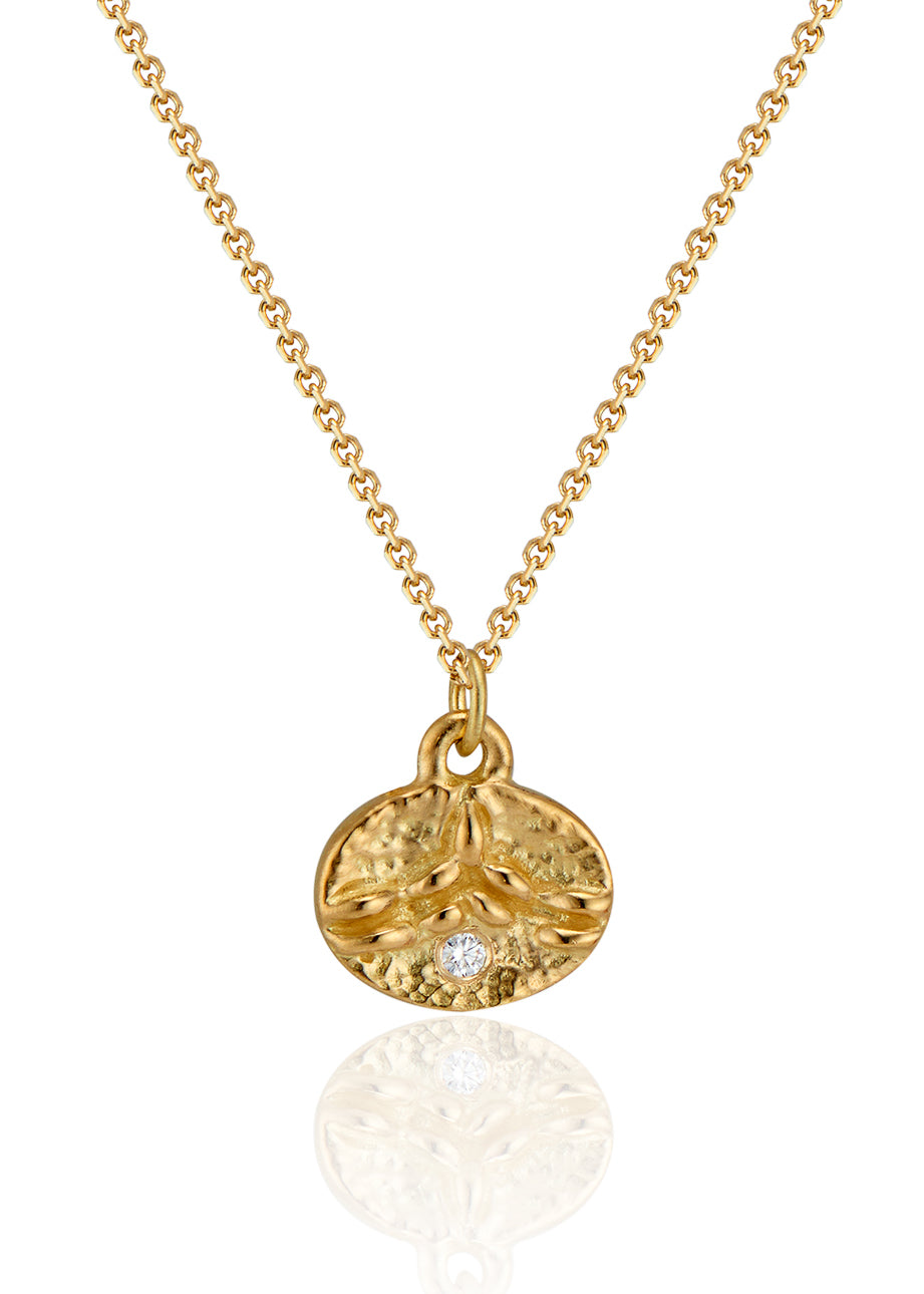 Inspired by the tiny beads of dew that cling to blades of grass on an early summer morning, the Dew necklace is hand-carved to reveal intricate texture and pattern across its coin-shaped pendant. A brilliant diamond catches the light, evocative of a dew drop itself—reflecting and refracting the beauty which surrounds it.