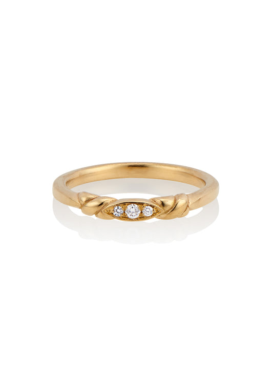 An engagement ring re-imagined, the Kiat ring was inspired by a proposal among sun-soaked cattails and waves lapping the shores of a hidden inlet. A gold band criss-crosses on either side of a trio of diamonds—a piece imbued with promise.