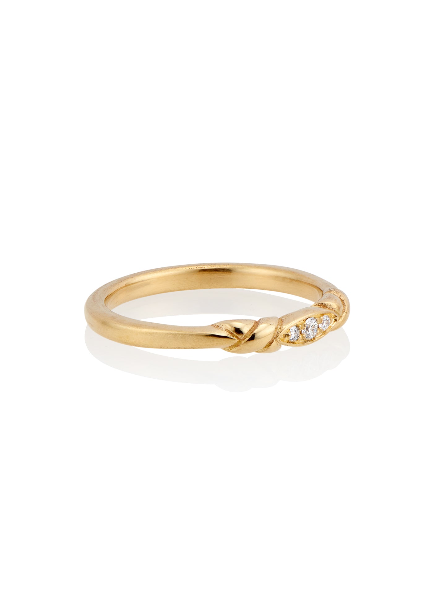 An engagement ring re-imagined, the Kiat ring was inspired by a proposal among sun-soaked cattails and waves lapping the shores of a hidden inlet. A gold band criss-crosses on either side of a trio of diamonds—a piece imbued with promise.