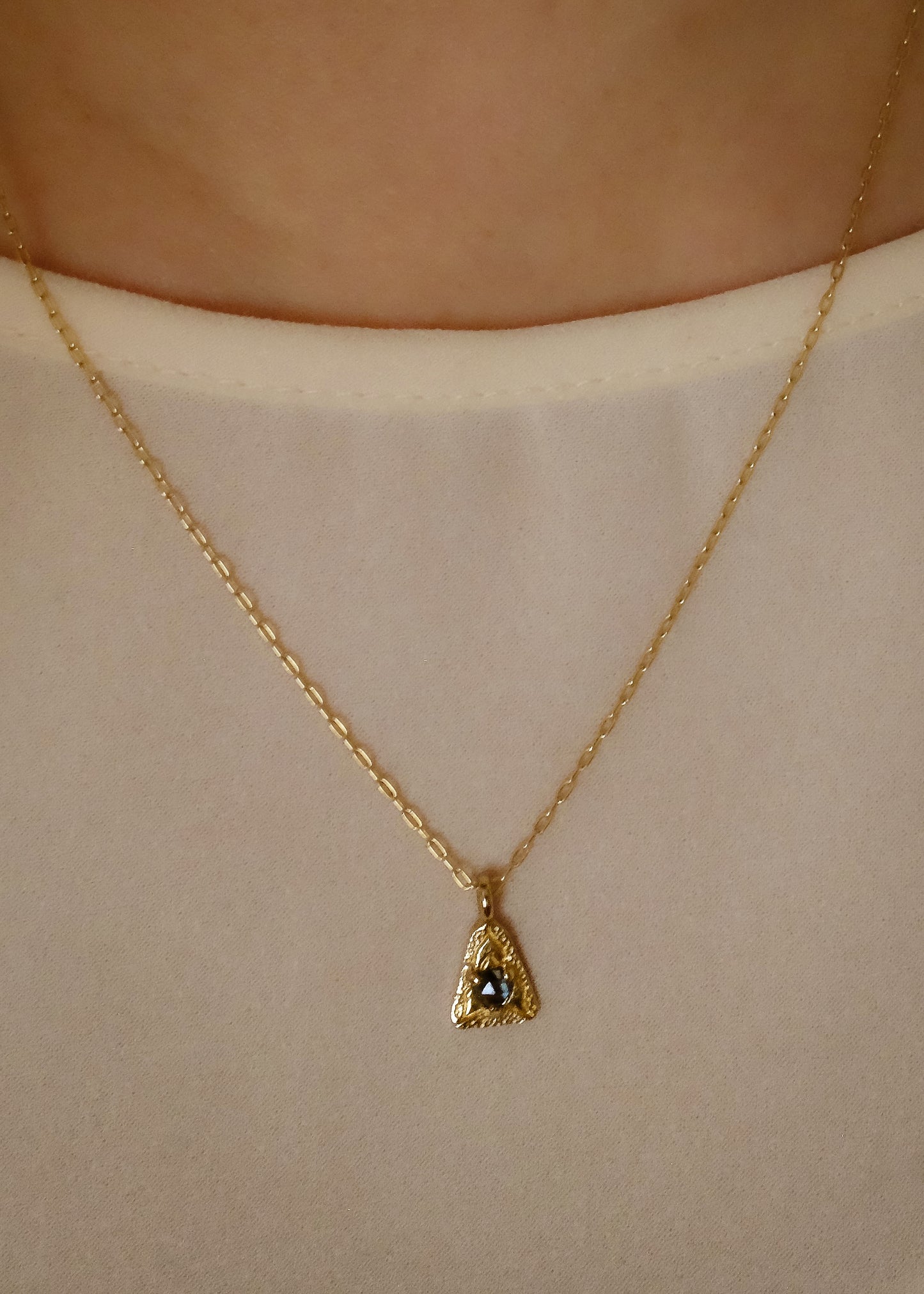 A celebration of resilience and strength. In nature, this water flower rises from the mud each day and blooms to its full potential. In architecture, the triangle is one of the strongest structures. The Blue Lotus necklace merges the natural elements of a rose cut blue sapphire and hand-carved gold lotus petals with an architecturally-inspired triangular pendant for a necklace of beauty and balance.