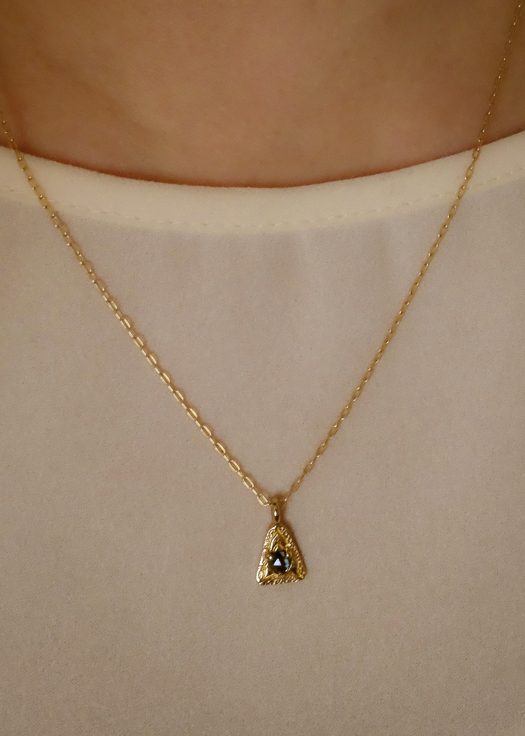 A celebration of resilience and strength. In nature, this water flower rises from the mud each day and blooms to its full potential. In architecture, the triangle is one of the strongest structures. The Blue Lotus necklace merges the natural elements of a rose cut blue sapphire and hand-carved gold lotus petals with an architecturally-inspired triangular pendant for a necklace of beauty and balance.