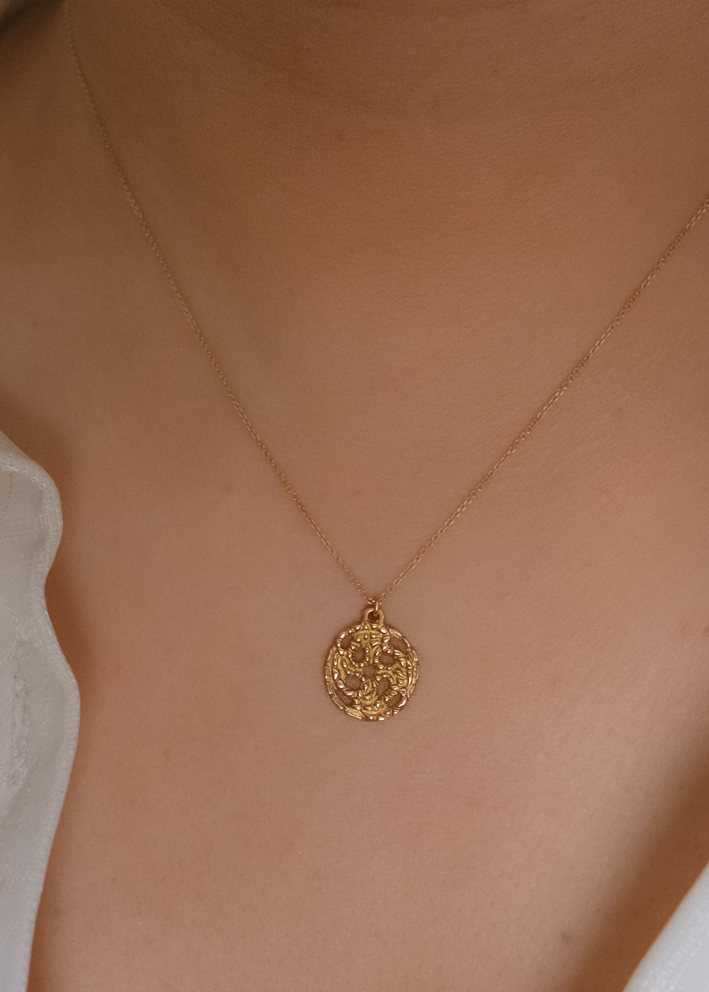 A passport to another world. With its intricate hand-carved texture and open-work design, the Token necklace calls to mind a lucky coin that opens the gate to where adventure lies, just beyond.