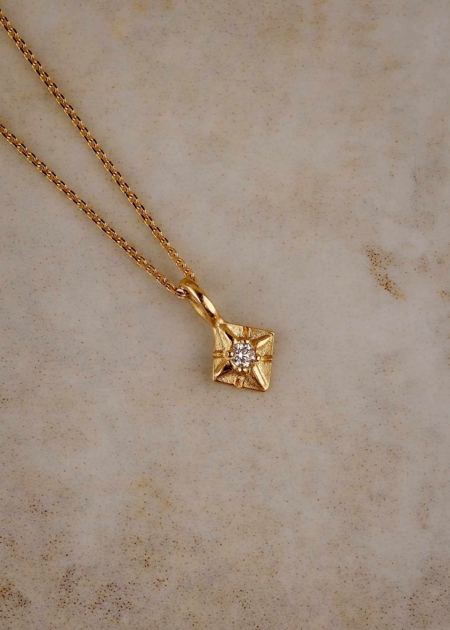 Through the sharp peak of a dormer window, a single star catches the eye: At the apex of the constellation it shines, as if hung by the starmaiden Astrea herself. Named for the Greek goddess, the Astrea necklace features a brilliant diamond that nestles between the zenith and nadir of a golden horizon. Hand-carved detail surrounding the diamond enhances its brilliance.