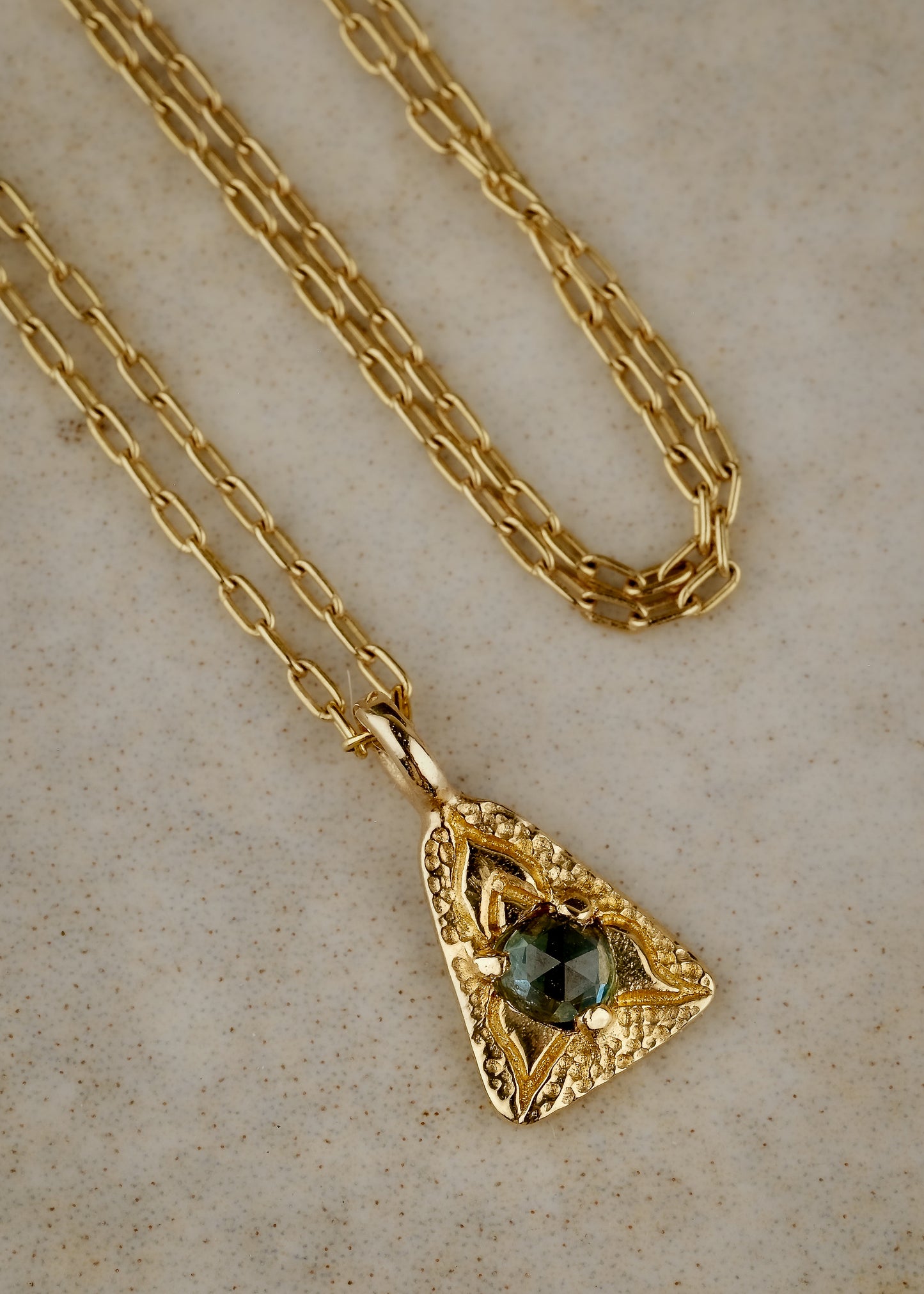 A celebration of resilience and strength. In nature, this water flower rises from the mud each day and blooms to its full potential. In architecture, the triangle is one of the strongest structures. The Blue Lotus necklace merges the natural elements of a rose cut blue sapphire and hand-carved gold lotus petals with an architecturally-inspired triangular pendant for a necklace of beauty and balance.