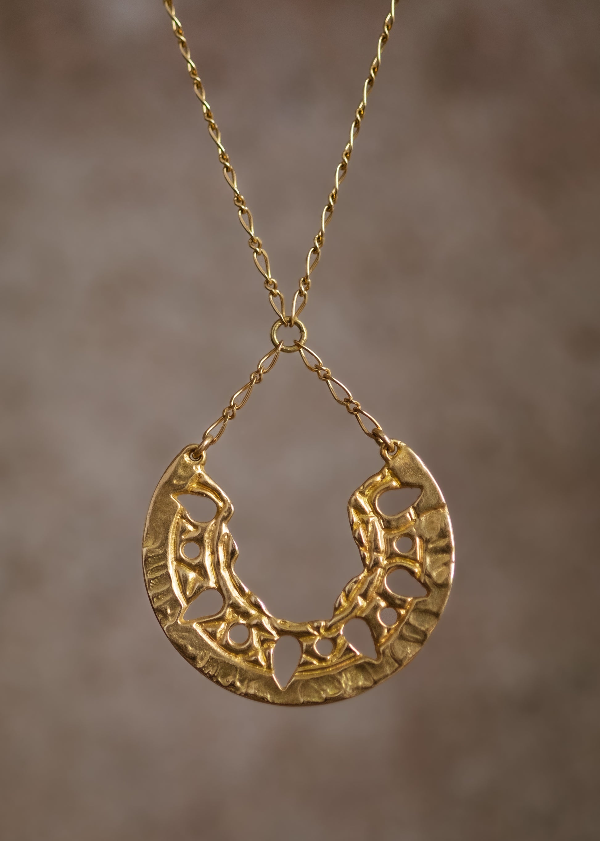 Sun-scorched sand. Glyphs that whisper centuries-old spells. Calling to mind the revered wesekh collars of ancient Egypt, the Demi necklace gleams in a crescent of textured gold. Punctuated with an arresting open-work pattern done by hand, this is a piece that harnesses the mysteries of a world shielded from time. 