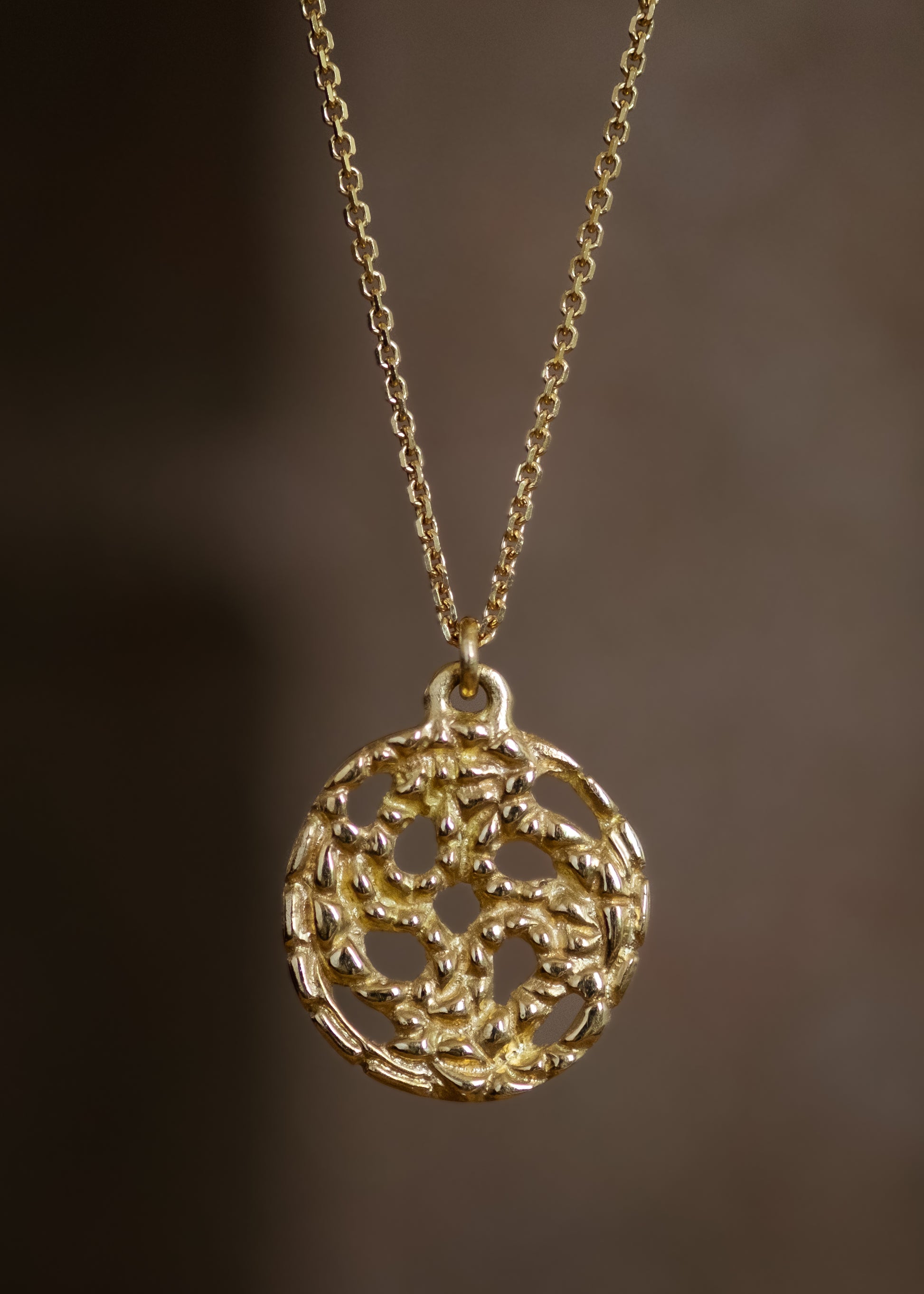 A passport to another world. With its intricate hand-carved texture and open-work design, the Token necklace calls to mind a lucky coin that opens the gate to where adventure lies, just beyond.