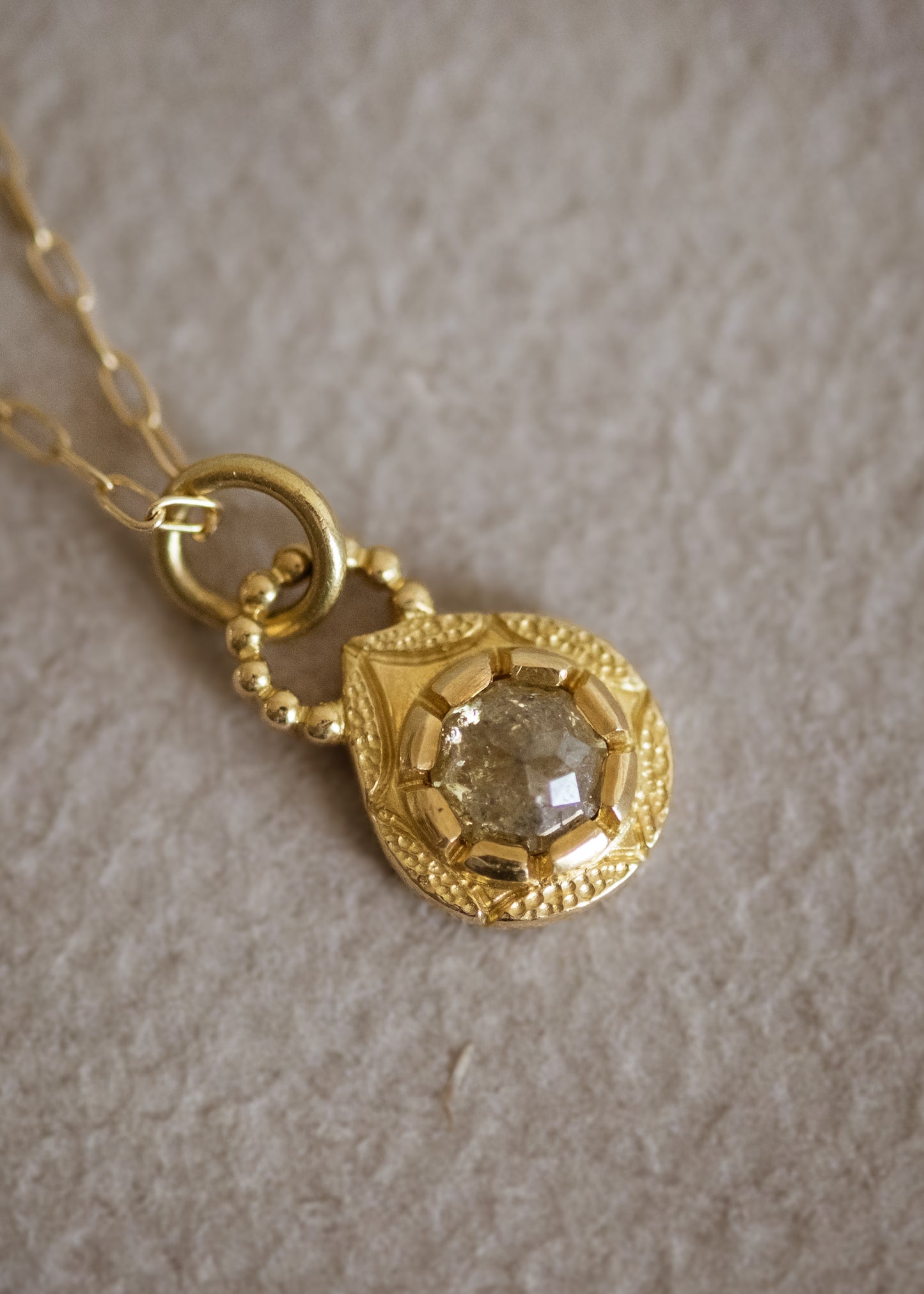 The Solo necklace revels in its unencumbered beauty. A stunning rose cut diamond is cradled in a gold droplet, revealing delicate texture and detail. An intricate beaded arch balances the pendant, linking it to its chain while showcasing its ornate character.