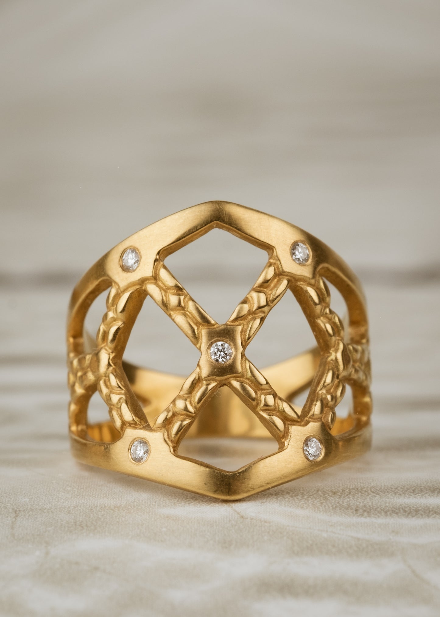 Named for the Norse goddess of love, gold and beauty, the Freya ring encapsulates fierce strength and unparalleled magnificence. Gold bands, both smooth and textured, criss cross around the finger to create open space—an architectural aegis highlighted by sparkling diamonds.