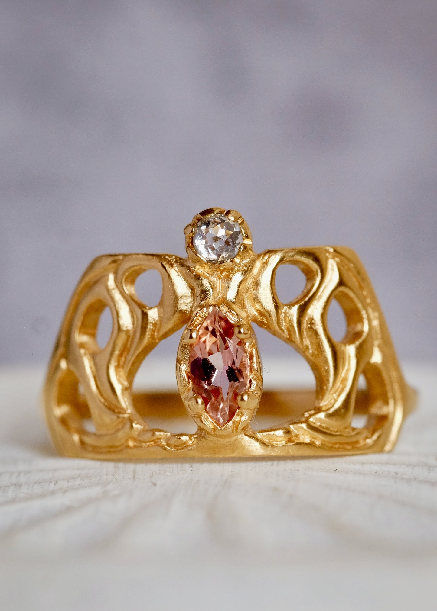 Framed by an intricate open-work pattern, the Anthea ring imagines the Greek goddess rendered in a window of stained glass, cradled by serpentine mullions of gleaming gold. A stunning tourmaline stone and rose cut diamond create a sensuous silhouette on this ring that bears her name.