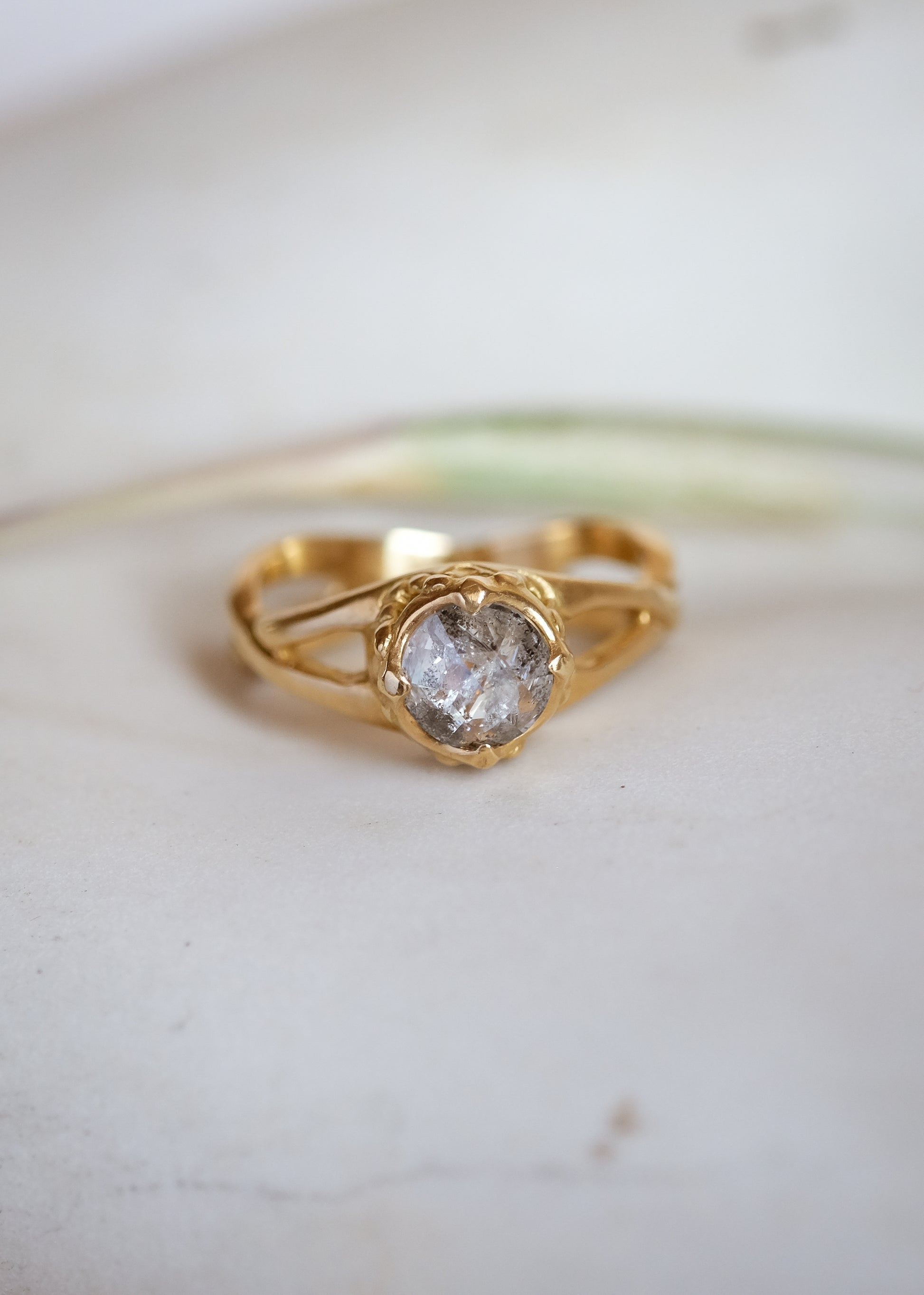 Capturing the Gothic beauty of a haunted mansion, the Liota ring is named for a woman whose gossamer spirit transcends time. Gold bands criss cross around the finger to buttress a brilliant rose cut diamond nestled among ornate carvings—an architectural ring that echoes the past while celebrating the eternal.