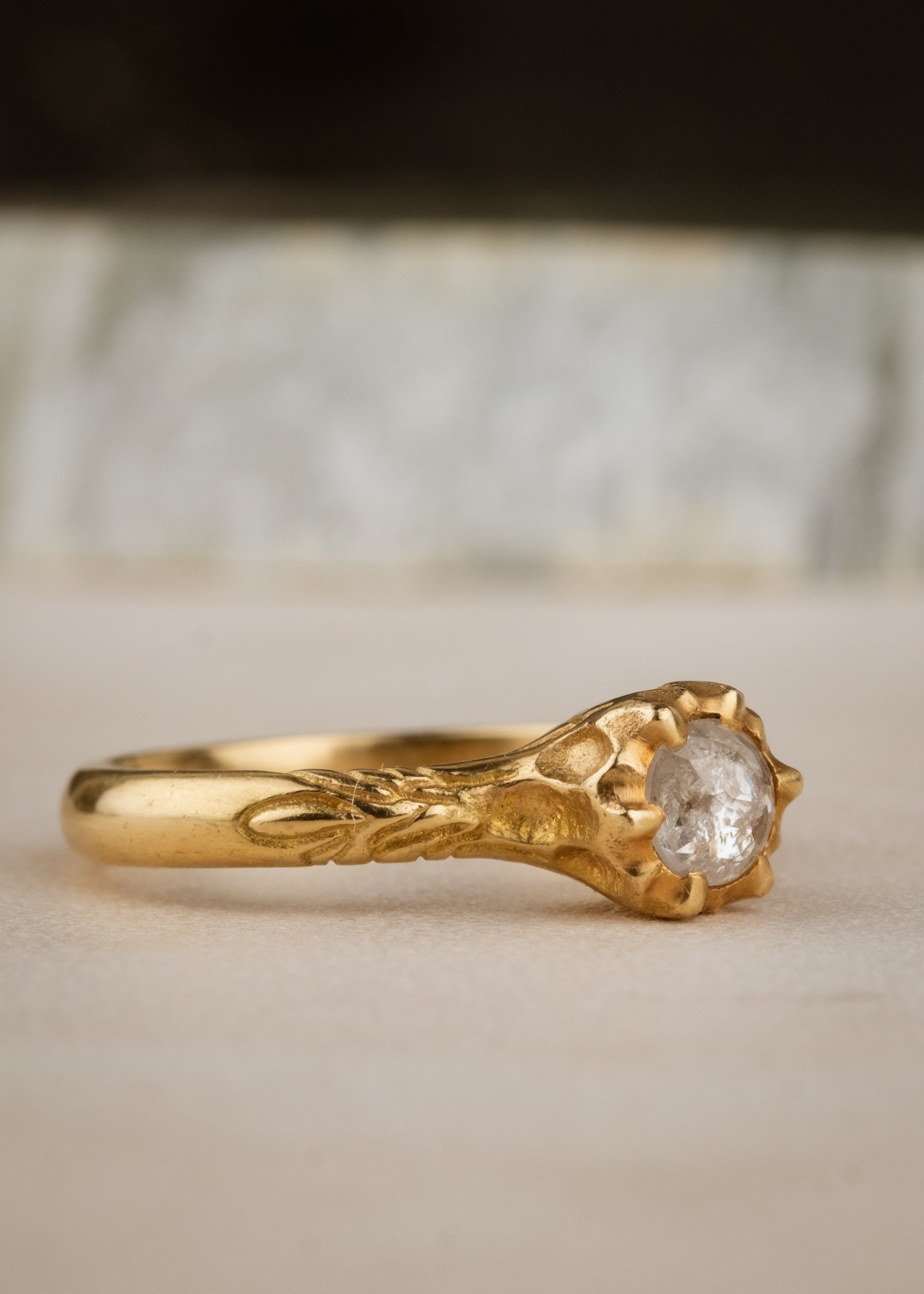 Like the haunting notes of a Glenn Miller Orchestra record, the Perfidia ring ascends to prominence on the finger to captivate all who bear witness to such beauty. Delicate details on the gold band give way to a textured pattern that holds a rose cut diamond, an exquisite work of ornate craftsmanship.