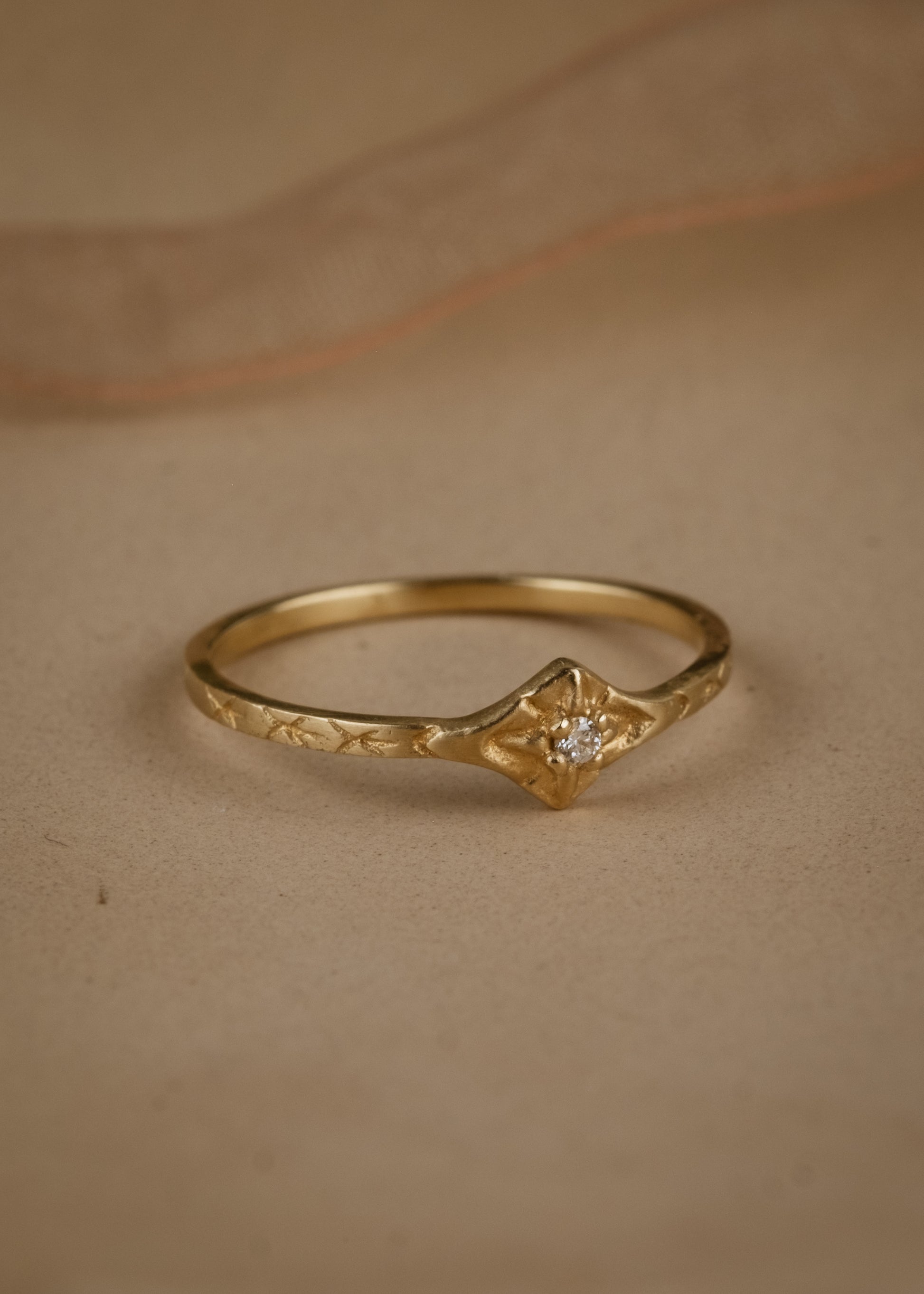 The smoke from a wood burning fire. A brilliant point of light piercing an obsidian sky. The Starlite ring captures the beauty of a frigid winter night. A brilliant diamond gleams against a delicate gold band that’s been intricately hand-carved with stars–a piece as timeless as the constellations themselves.
