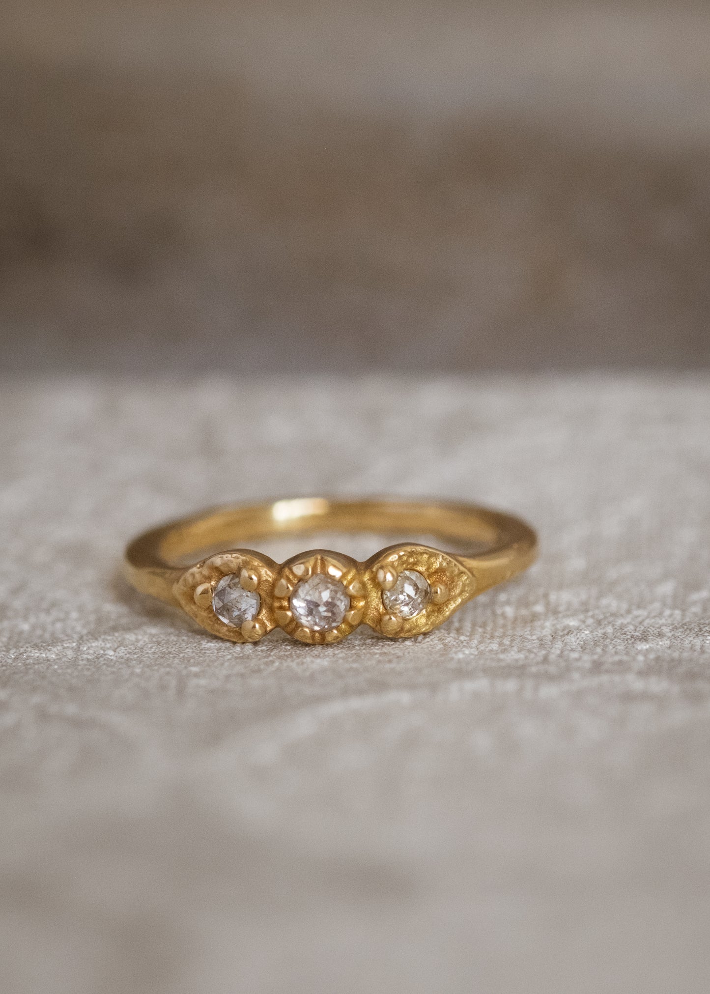 With a timeless and romantic aesthetic, the Trio ring showcases a gold band that has been hand-designed to create delicate beading and texture, encasing three luminous rose cut diamonds—an old world style reimagined for our modern moment.