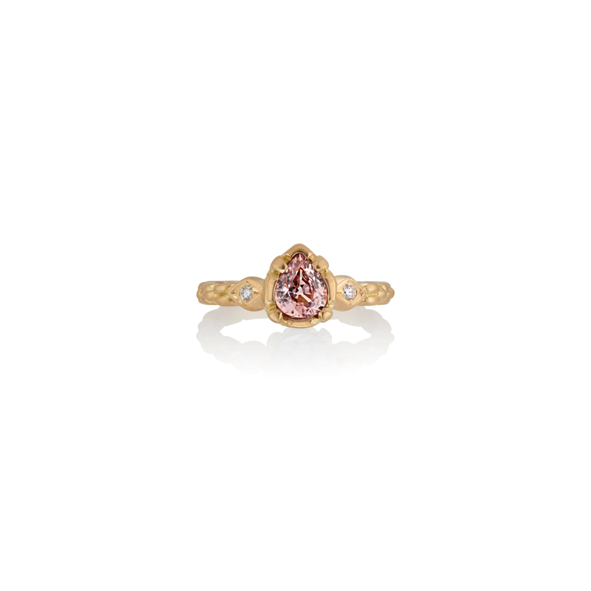 Stately and elegant, the Majestic ring is rich in exquisitely carved gold detail along the band, securing a pear-shaped pink zircon that commands attention—a piece evocative of royalty. 