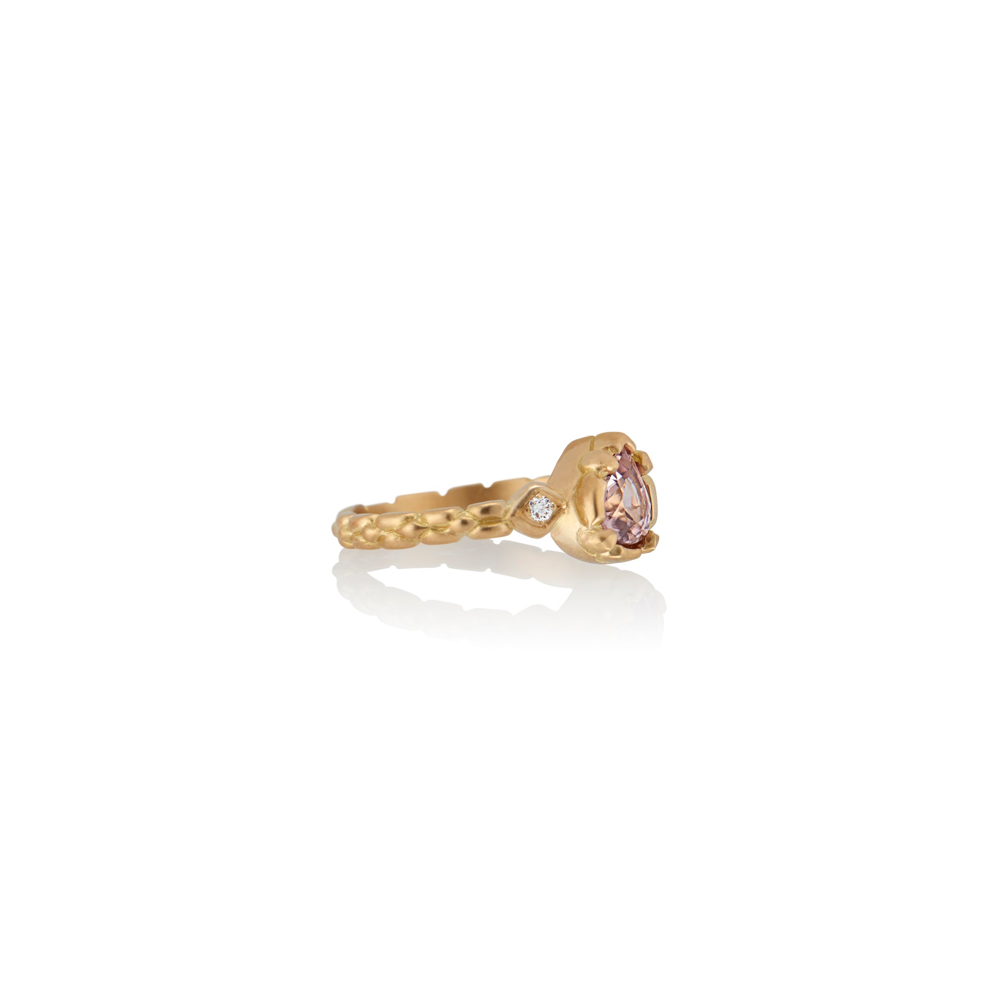 Stately and elegant, the Majestic ring is rich in exquisitely carved gold detail along the band, securing a pear-shaped pink zircon that commands attention—a piece evocative of royalty. 