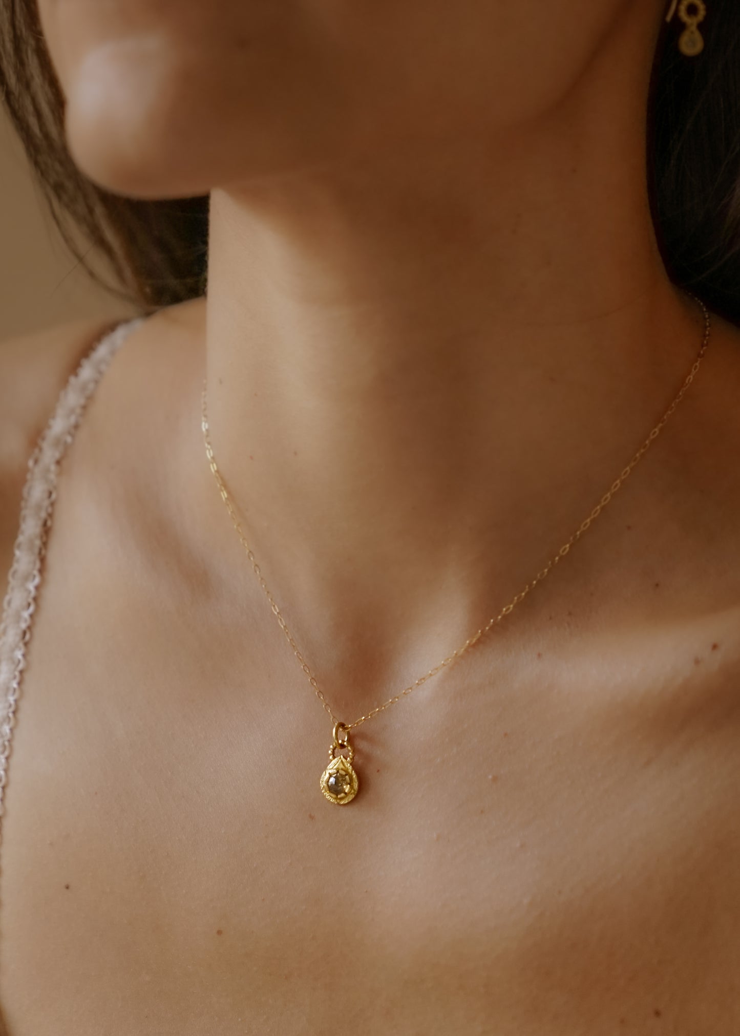 The Solo necklace revels in its unencumbered beauty. A stunning rose cut diamond is cradled in a gold droplet, revealing delicate texture and detail. An intricate beaded arch balances the pendant, linking it to its chain while showcasing its ornate character. 
