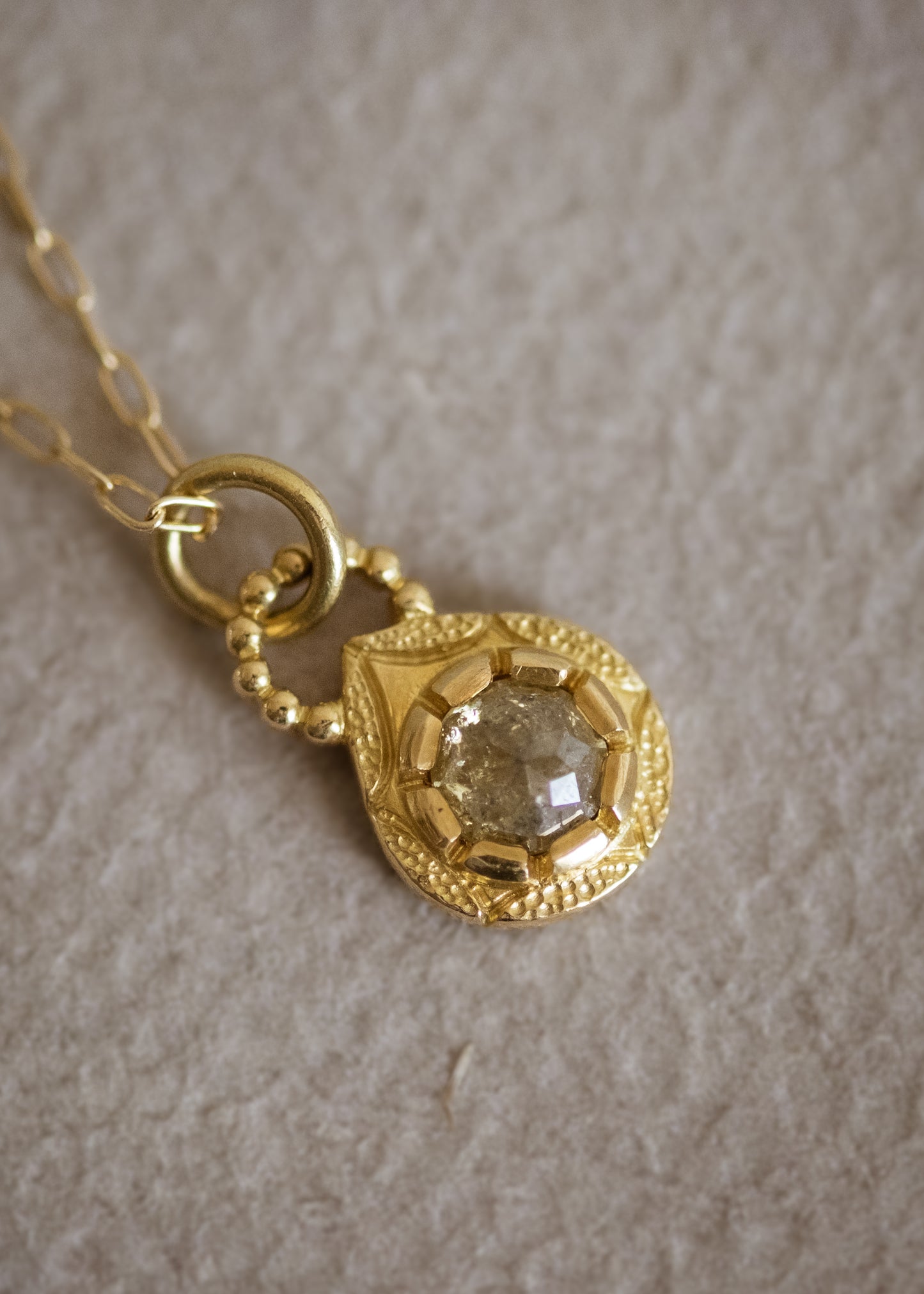 The Solo necklace revels in its unencumbered beauty. A stunning rose cut diamond is cradled in a gold droplet, revealing delicate texture and detail. An intricate beaded arch balances the pendant, linking it to its chain while showcasing its ornate character. 