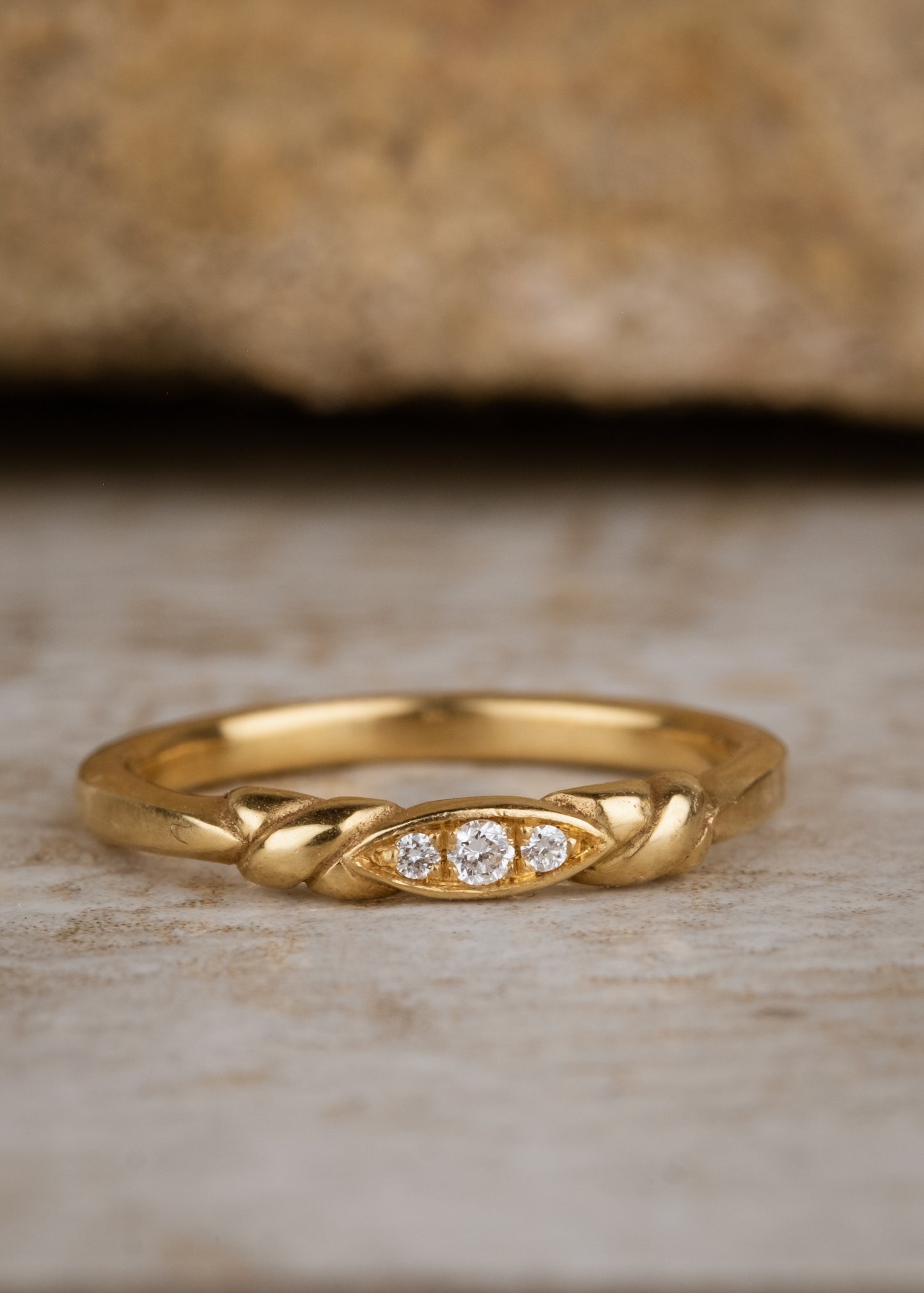 An engagement ring re-imagined, the Kiat ring was inspired by a proposal among sun-soaked cattails and waves lapping the shores of a hidden inlet. A gold band criss-crosses on either side of a trio of diamonds—a piece imbued with promise. 